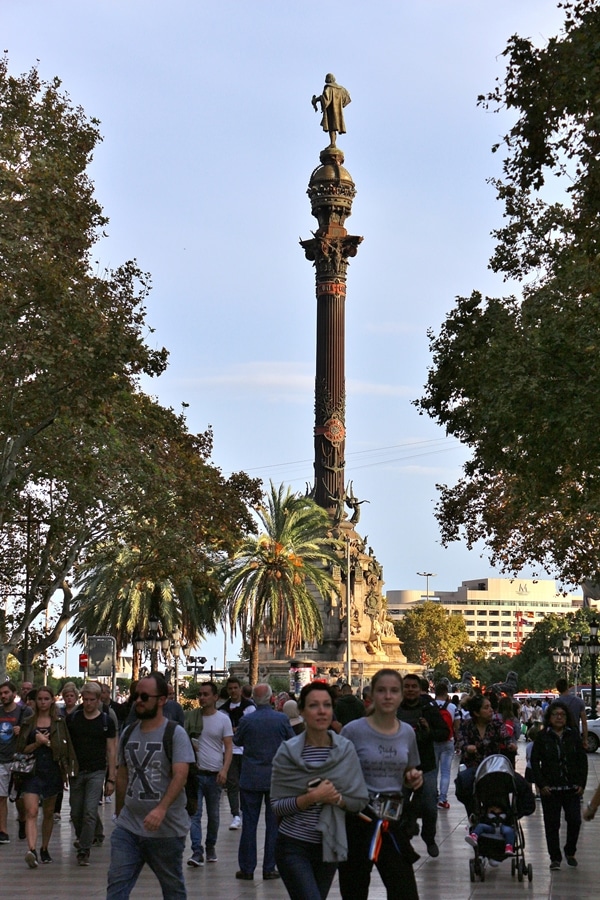 A group of people walking in front of a tall monument