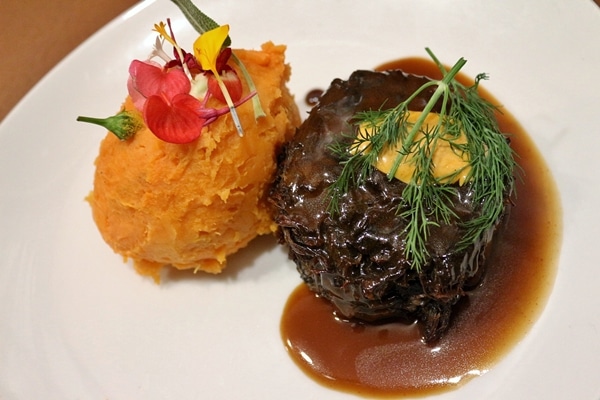 braised beef cheeks and mashed sweet potato on a white plate