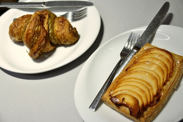 a croissant and apple tart on white plates