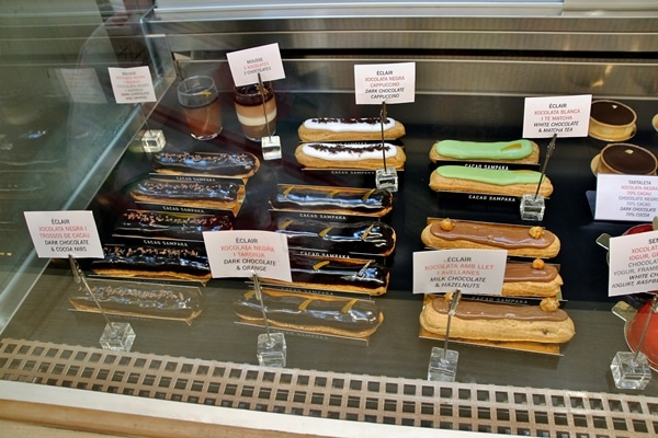 a variety of eclairs in a pastry display case