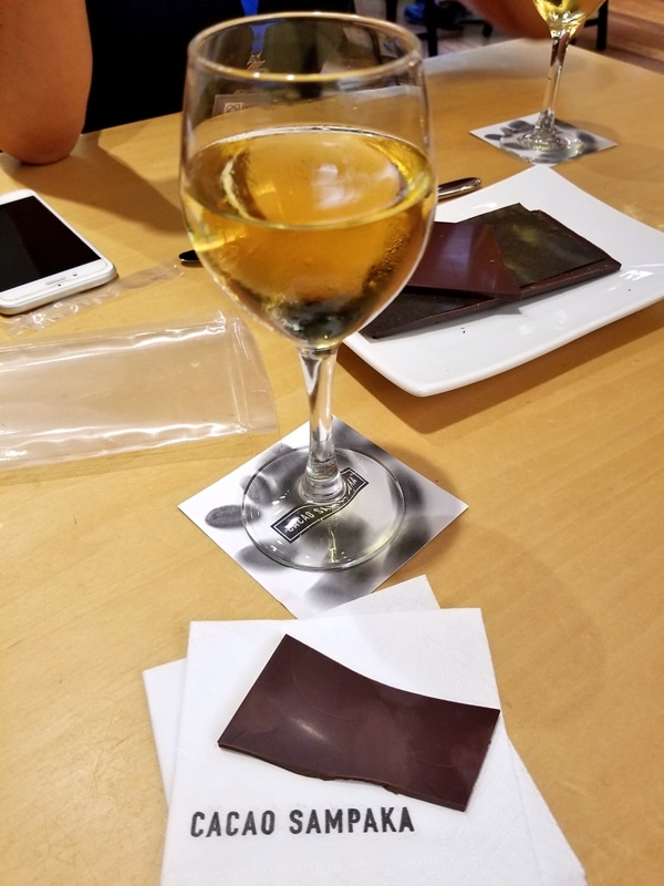 A glass of wine and a bar of chocolate on a wooden table