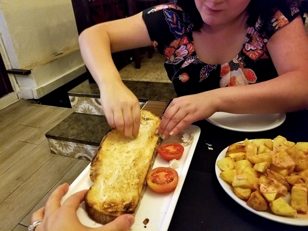 A woman rubbing a piece of garlic on a slice of toasted bread