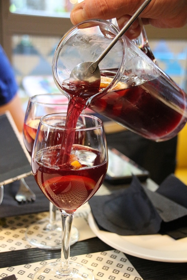 pouring glasses of sangria from a glass pitcher