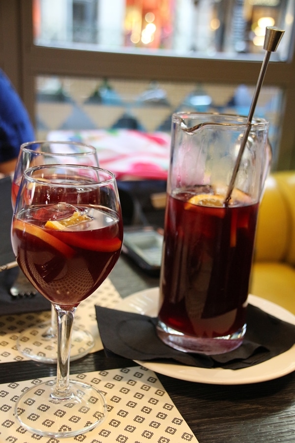 2 glasses of red sangria next to a pitcher of sangria