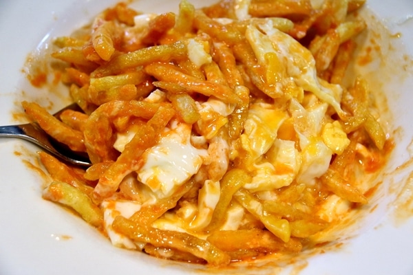 a mixture of french fries with cut up egg and sauce in a white dish