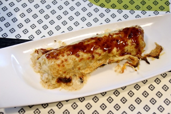 a cannelloni topped with brown sauce on a small white plate