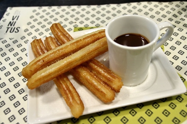 a plate of fried churros with dipping chocolate