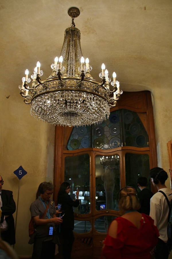 A group of people standing in a room under a chandelier