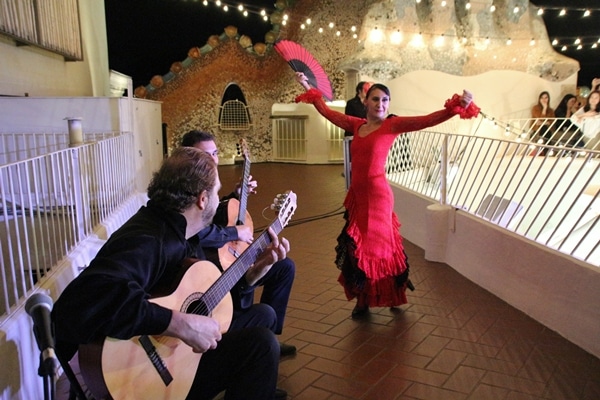 A group of people playing the guitar next to a flamenco dancer wearing red