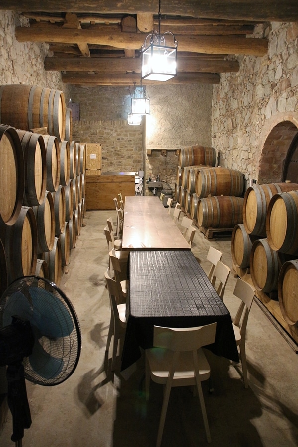 a room filled with wine barrels and a couple tables with chairs