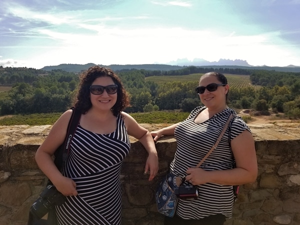 2 women posing in front of a vineyard