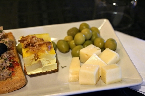 closeup of cheese cubes and green olives on a white plate