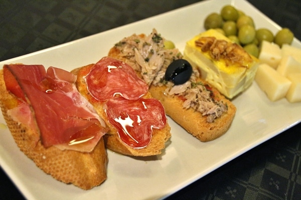 a variety of Spanish tapas arranged on a white plate