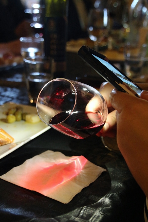 A close up of a person holding a wine glass and shining a light through it