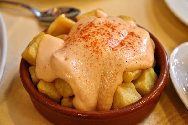 close up of a dish of fried potatoes topped with pink sauce