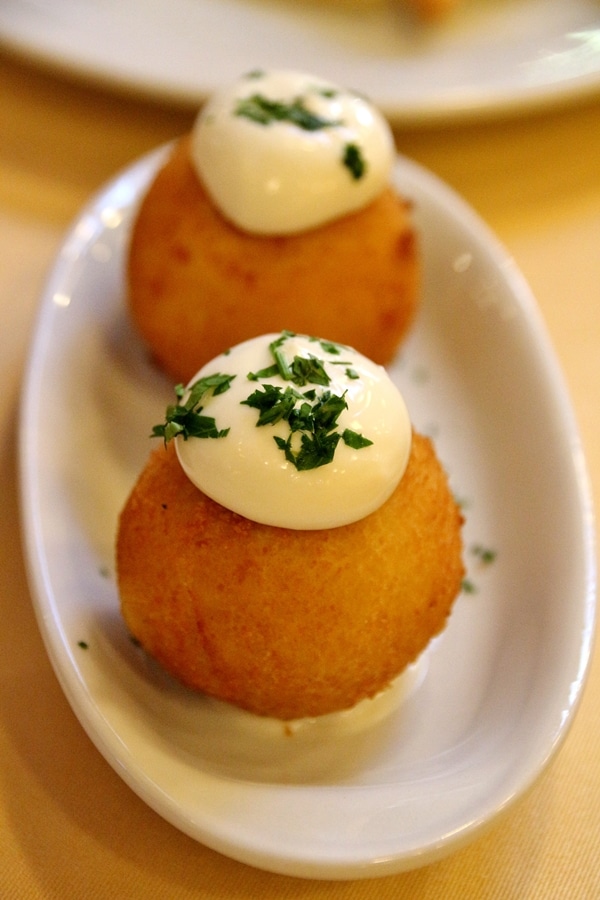 closeup of 2 fried potato balls on a white plate