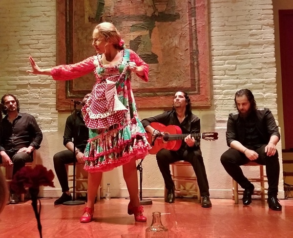 a female flamenco dancer in pink on a stage with musicians