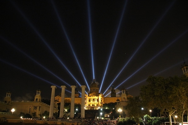 lights shining up from behind a large building at night