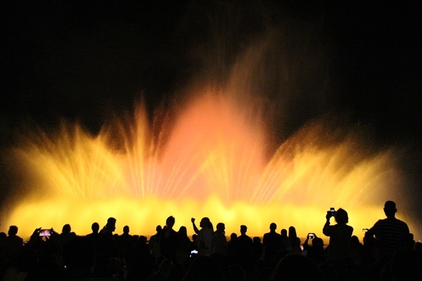 a crowd of people in front of a colorful water fountain at night