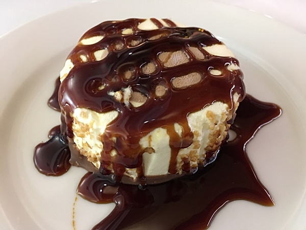 a slice of dessert topped with chocolate sauce