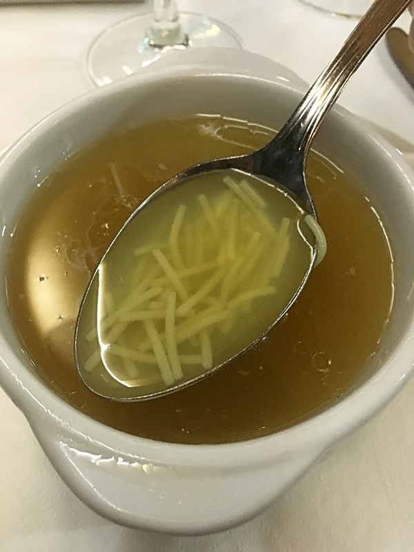 A bowl of noodle soup and a spoon