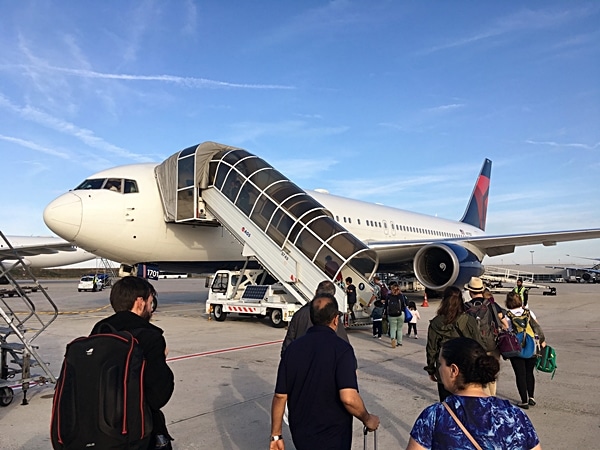 A large passenger jet sitting on the tarmac with people standing around a plane