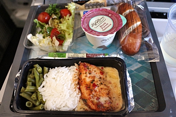 a tray of airplane food featuring chicken with rice and salad