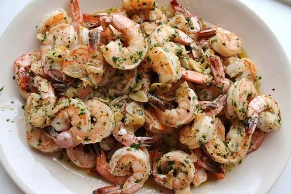 A platter of Spanish garlic shrimp with sliced garlic and parsley