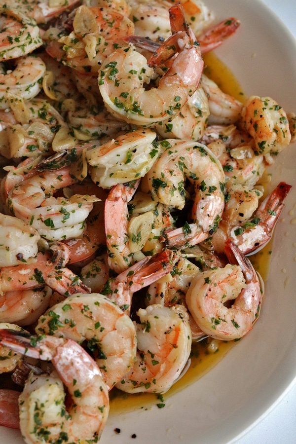 A platter of shrimp with sliced garlic and chopped parsley
