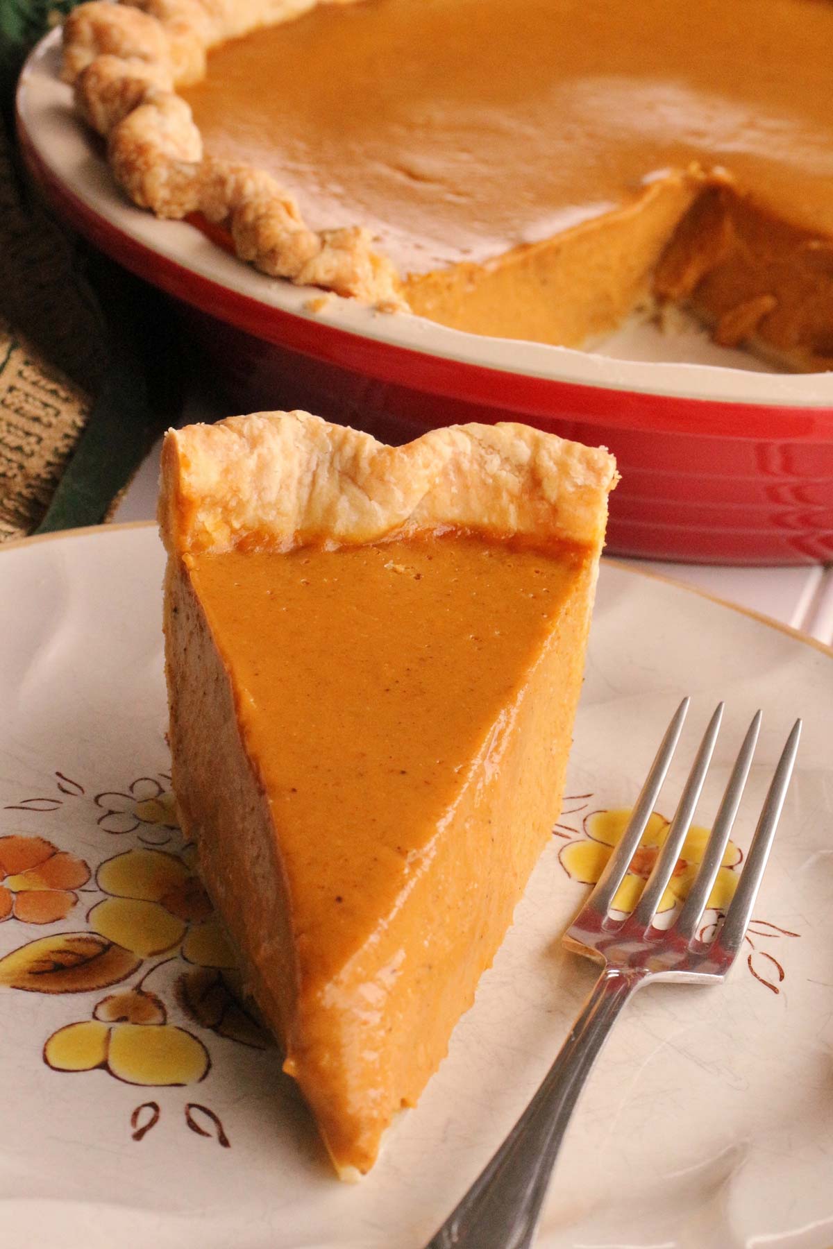 A slice of brown butter pumpkin pie on a plate with a fork next to it.