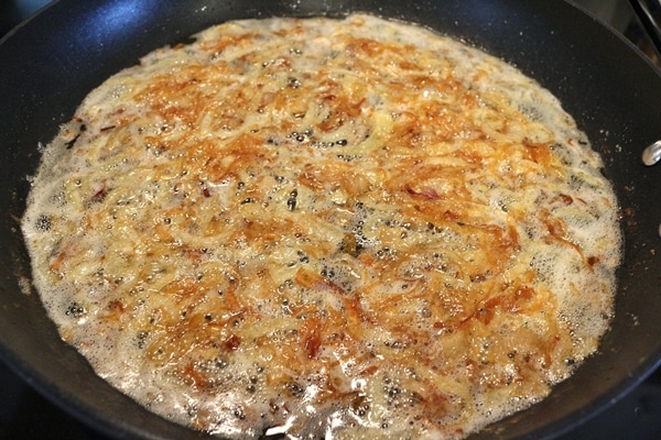 Sliced onions and shallots frying in a skillet