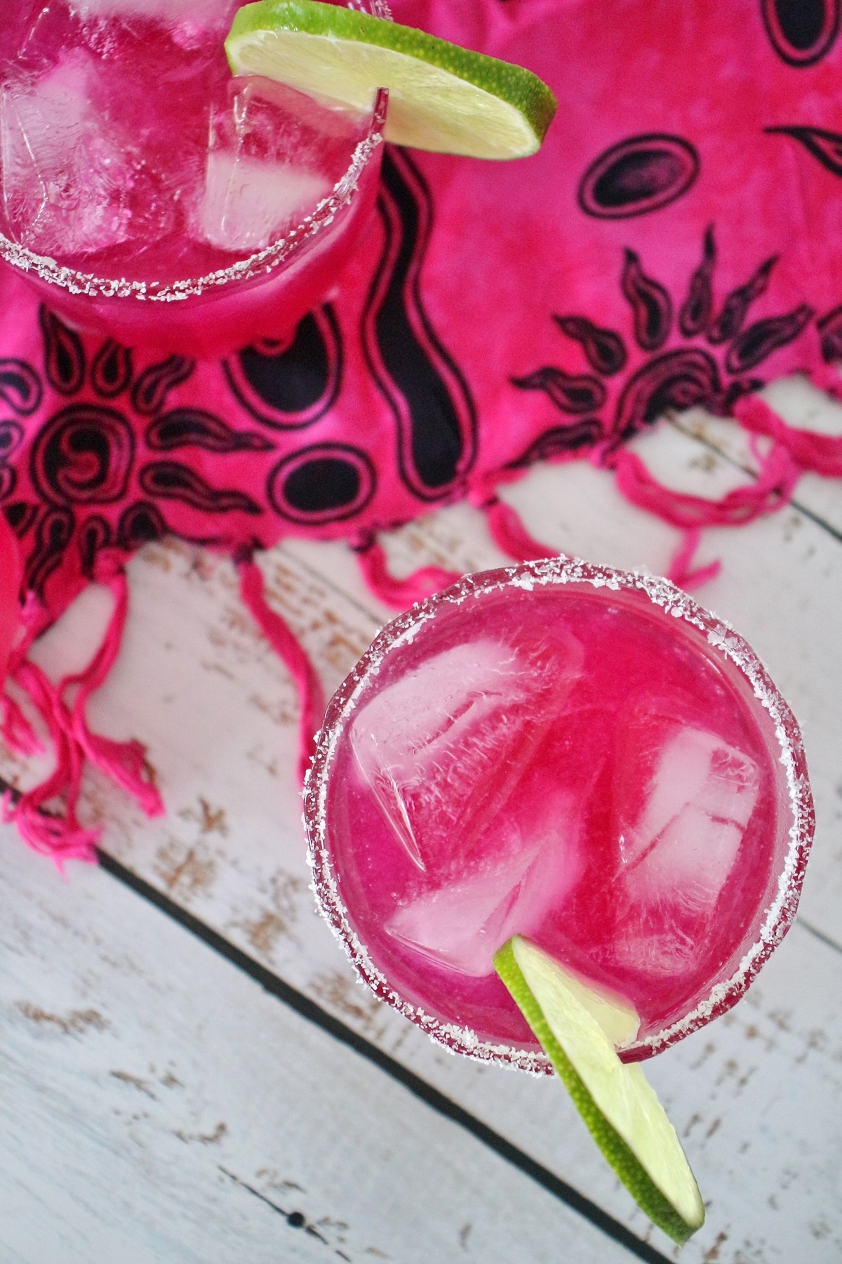 2 prickly pear margaritas in glass tumblers with lime slice garnish.