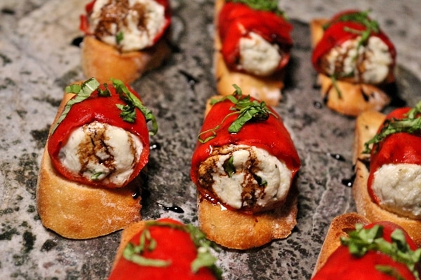 Stuffed piquillo peppers with goat cheese on sliced baguettes on a granite serving dish