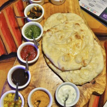 Sanaa bread service with a pile of naan surrounded by cups of dipping sauces.