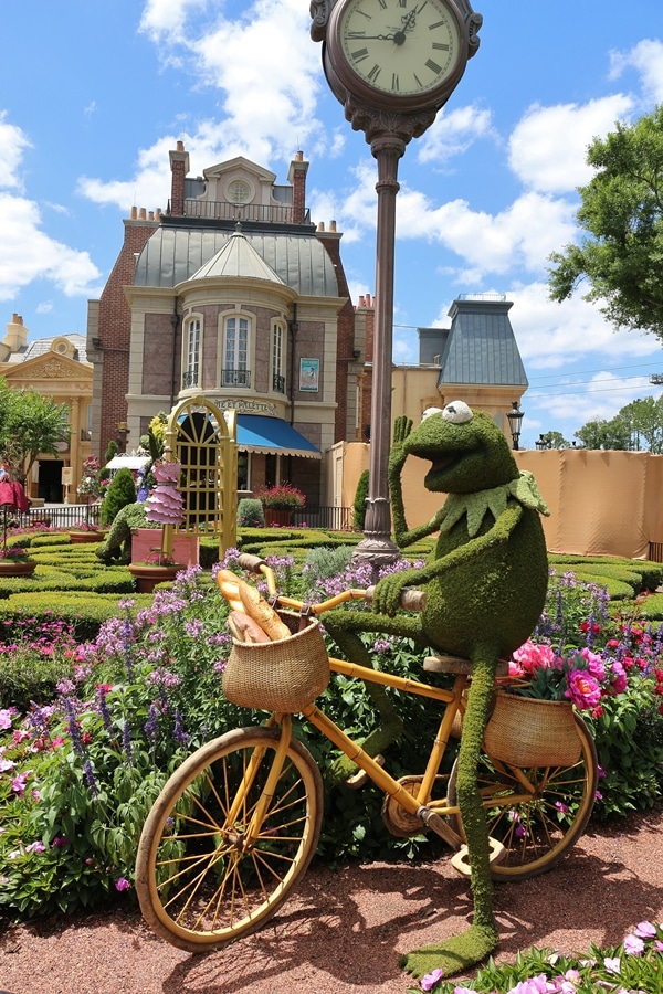 a topiary shaped like Kermit riding a bicycle