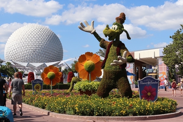 a topiary shaped like Goofy with Spaceship Earth in the background