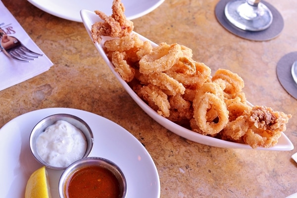 a small platter of fried calamari with dipping sauces on the side