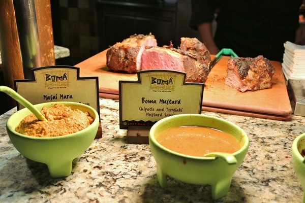 2 bowls of sauce in front of a cutting board topped with roast beef