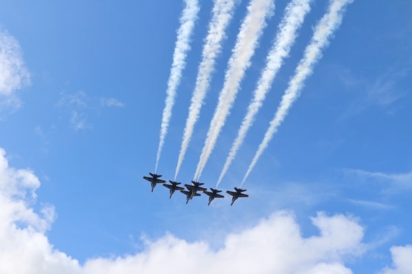 the Blue Angels fighter jets flying through a cloudy blue sky