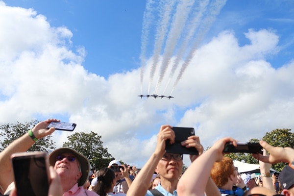 fighter jets flying over a group of people