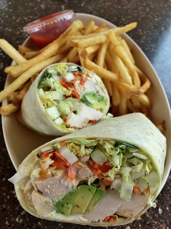 closeup of a halved chicken wrap with fries