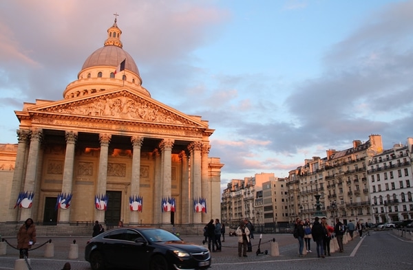 A group of people walking in front of the Pantheon in Paris