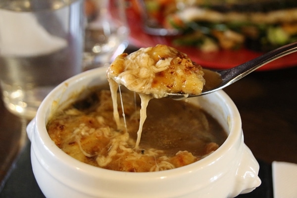 closeup of a spoon of French onion soup with melted cheese