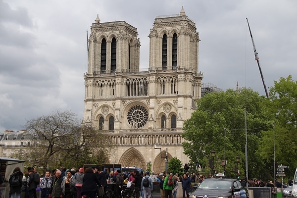 A group of people walking in front of Notre Dame de Paris