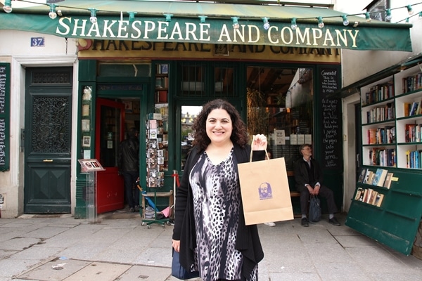 A person standing in front of a store holding a paper bag