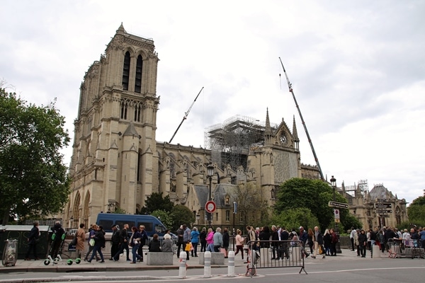 A group of people walking in front of Notre Dame Cathedral