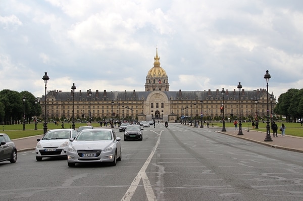 Les Invalides building with its gold dome at the end of a busy street