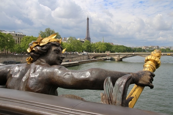 A statue of a man with the Eiffel Tower in the distance