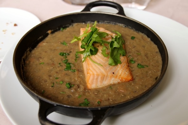 a wide pan of lentils topped with a fillet of salmon