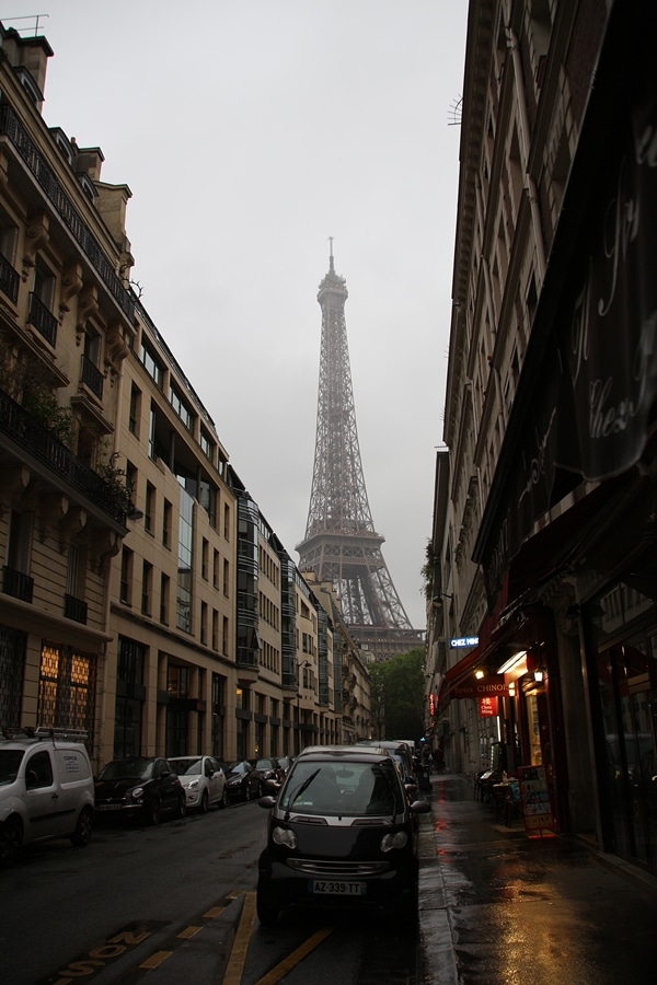 a rainy city street with the Eiffel Tower in the distance